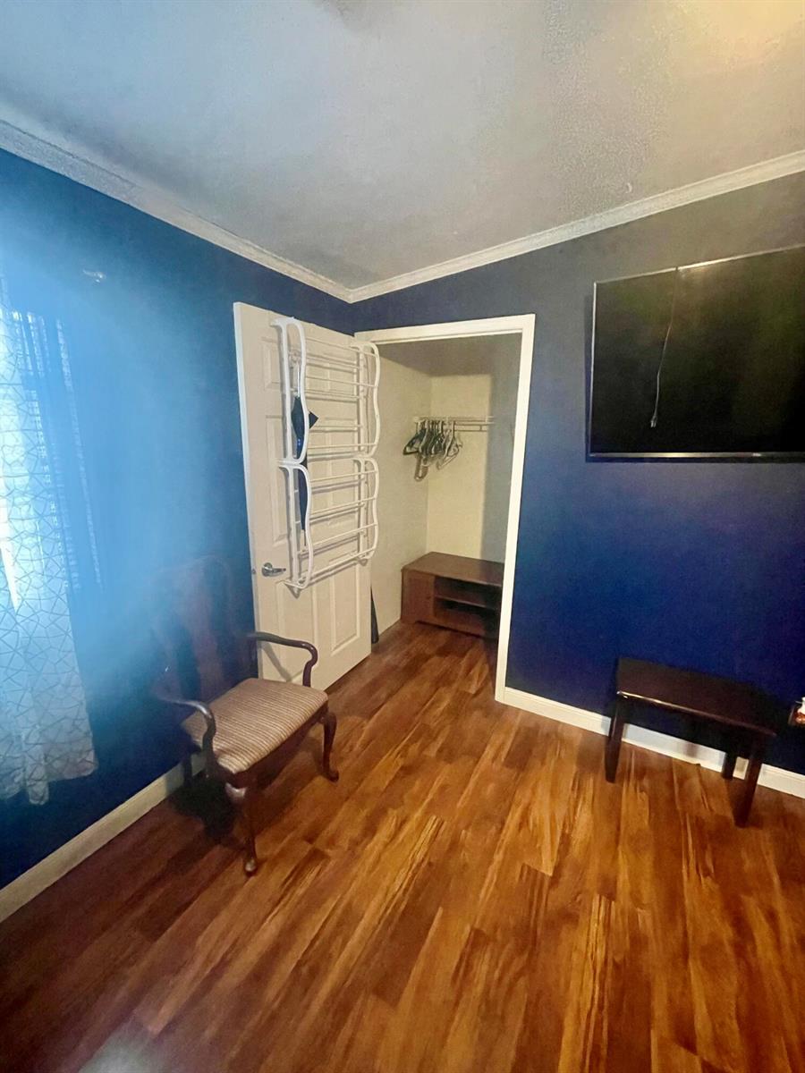 A bedroom with dark blue walls, wood-look flooring, a closet, and a mounted television — 195 Plantation Boulevard, Lake Worth FL 33467, LAKE WORTH, FL