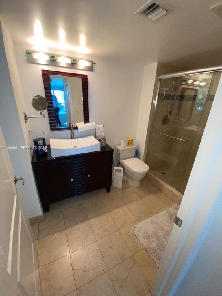 A bathroom features a vessel sink vanity, a glass-enclosed shower, and light-colored floor tiles — 2101 Brickell Ave # 2604, Miami FL 33129, MIAMI, FL
