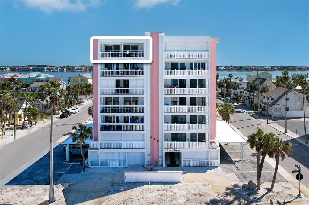 An exterior view of a multi-story apartment building with a highlighted top-floor balcony — 555 GULF WAY UNIT 7N, ST PETE BEACH, FL