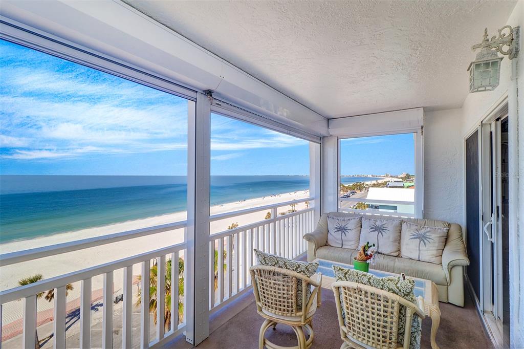 A balcony with wicker furniture overlooks a sandy beach and the ocean — 555 GULF WAY UNIT 7N, ST PETE BEACH, FL