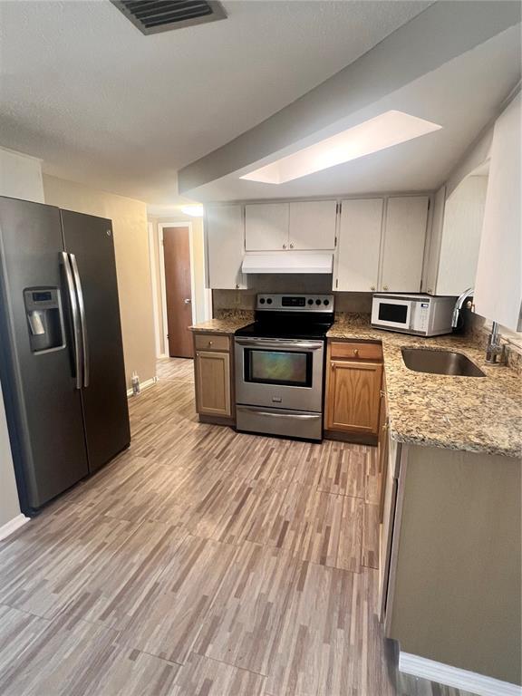 A kitchen features stainless steel appliances, granite countertops, and two-toned wood and white cabinets — 9910 LAKE CHRISE LANE, PORT RICHEY, FL