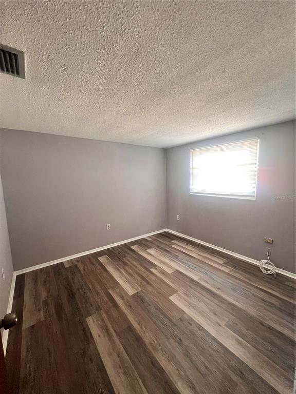 An empty bedroom with gray walls, wood-look flooring, and a single window with blinds — 9910 LAKE CHRISE LANE, PORT RICHEY, FL