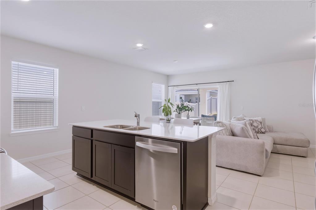 A kitchen island with a stainless steel dishwasher faces a living area with a sofa — 3535 WEAVER WAY, DAVENPORT, FL
