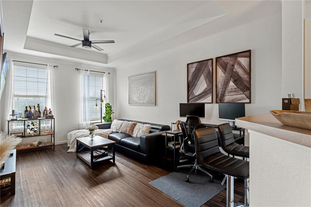 A living room features a black leather sofa, a coffee table, and a home office area — 4221 W SPRUCE STREET UNIT 2423, TAMPA, FL