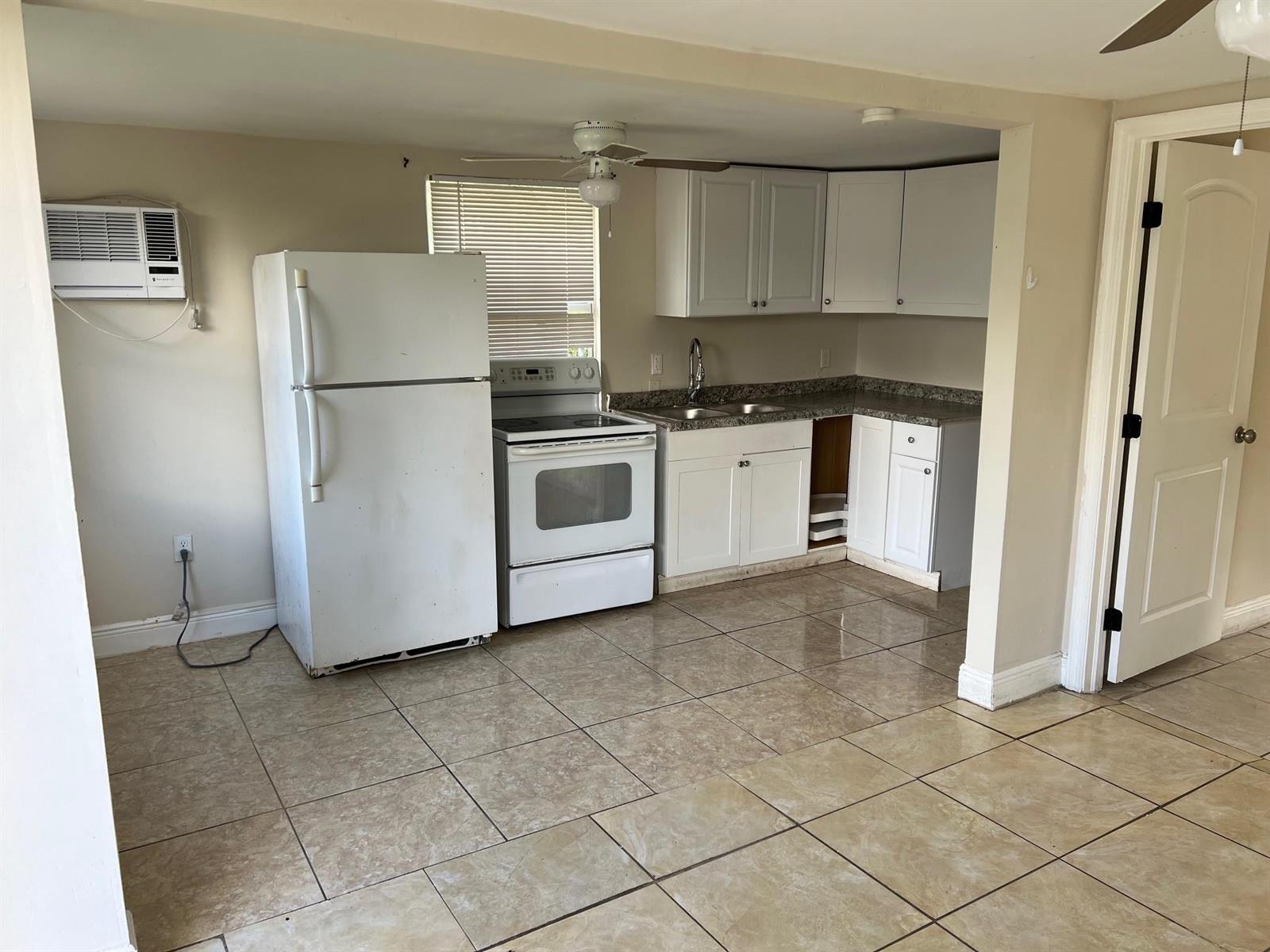 A kitchen features white cabinets, a white stove and refrigerator, and tan tile flooring — 8269 NW 1st Place # 2, Miami FL 33150, MIAMI, FL