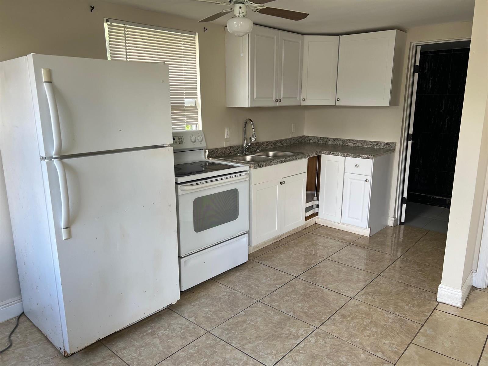 A kitchen features white cabinets, a white refrigerator, a white stove, and tiled flooring — 8269 NW 1st Place # 2, Miami FL 33150, MIAMI, FL