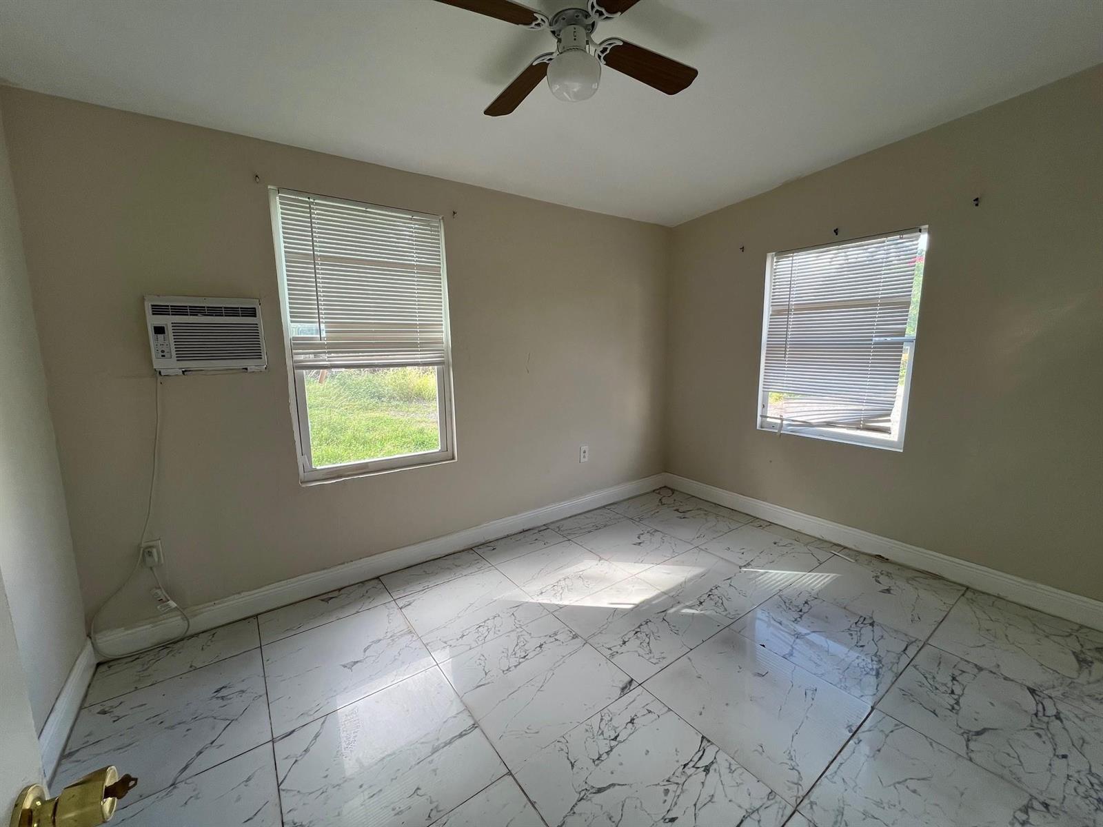 An empty bedroom features light beige walls, white marble-patterned tile flooring, and two windows — 8269 NW 1st Place # 2, Miami FL 33150, MIAMI, FL