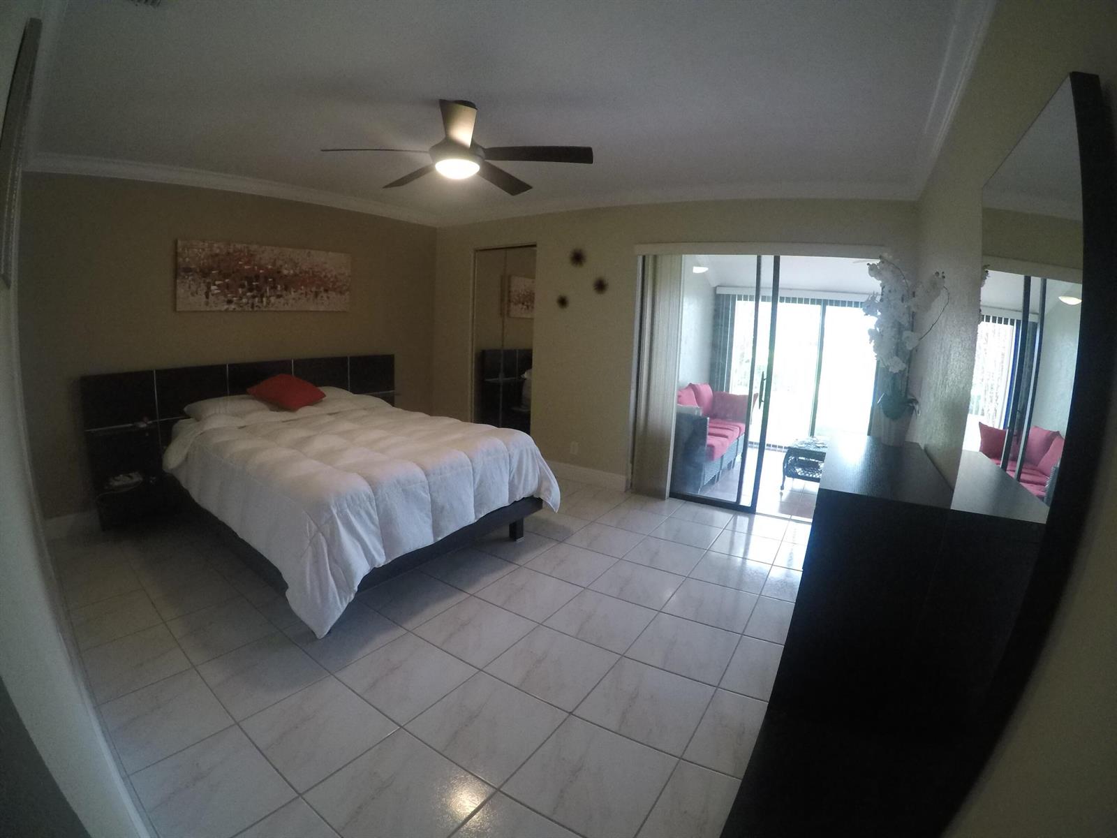 A bedroom with white tile floors, a dark wood headboard, and sliding glass doors to a balcony — 633 Sea Pine Way # C, FL 33415, FL