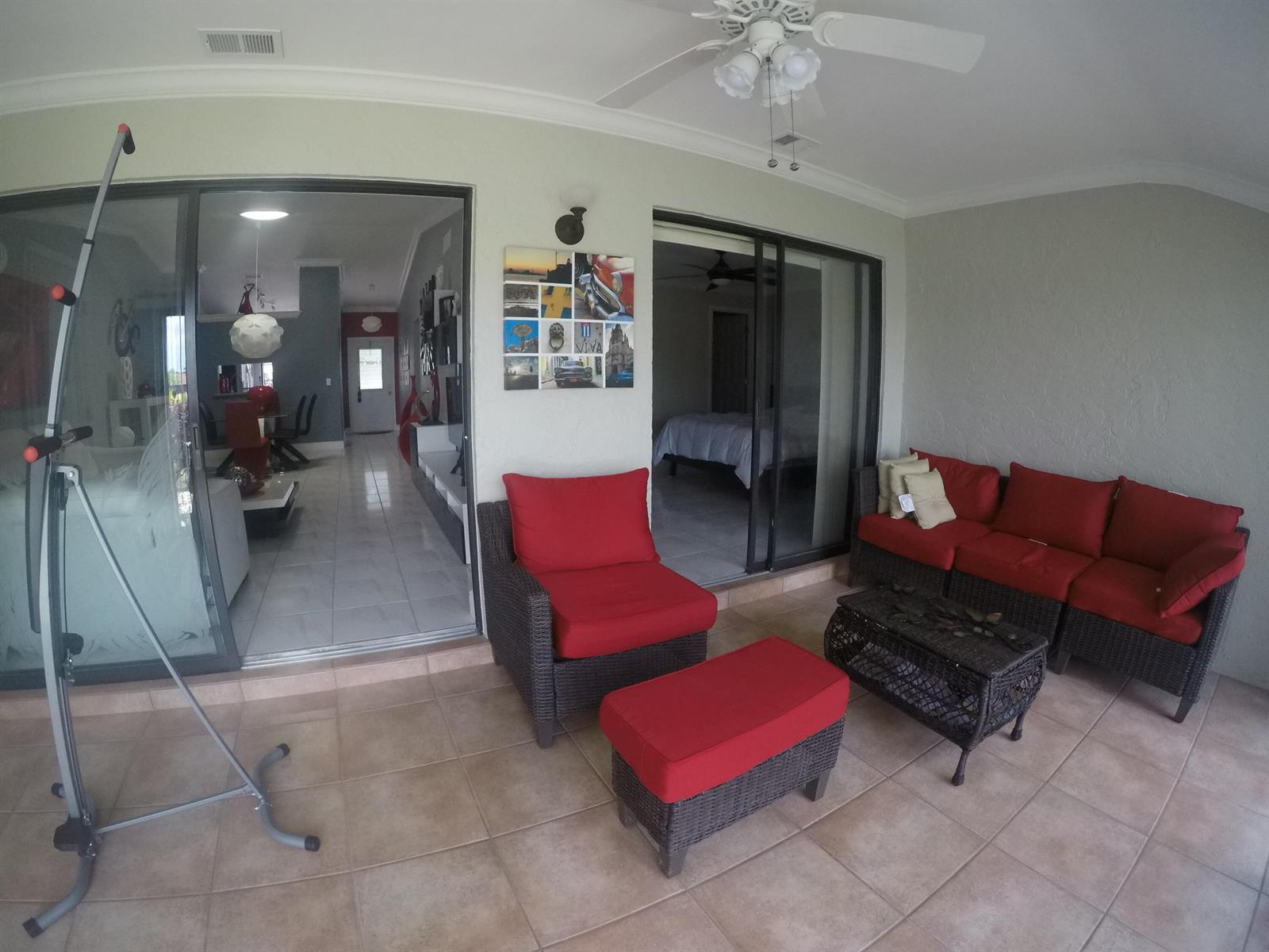 A covered patio features wicker furniture with red cushions, tile flooring, and sliding glass doors — 633 Sea Pine Way # C, FL 33415, FL