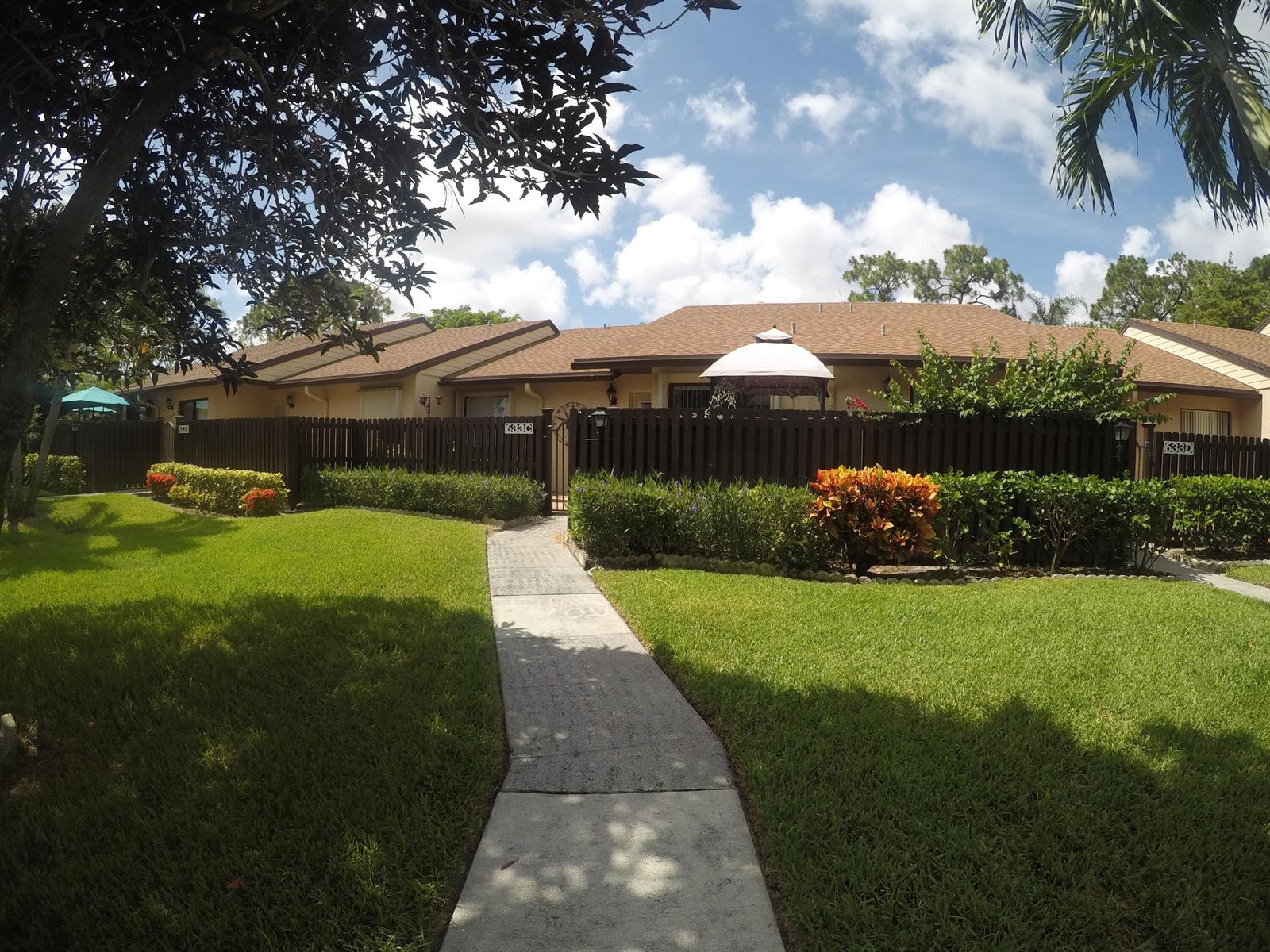 A sidewalk leads to the entrance of a single-story residential building with a brown fence — 633 Sea Pine Way # C, FL 33415, FL