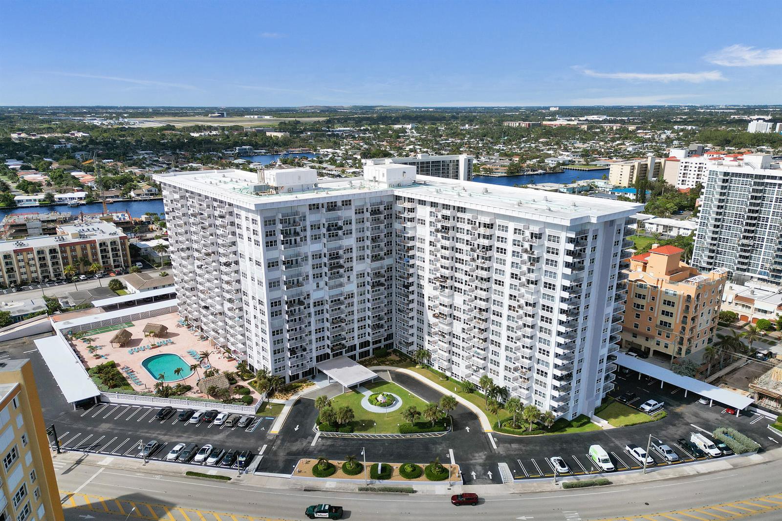 An aerial view shows a large white apartment building with a pool and parking lot — 405 N Ocean Boulevard # 305, Pompano Beach FL 33062, POMPANO BEACH, FL