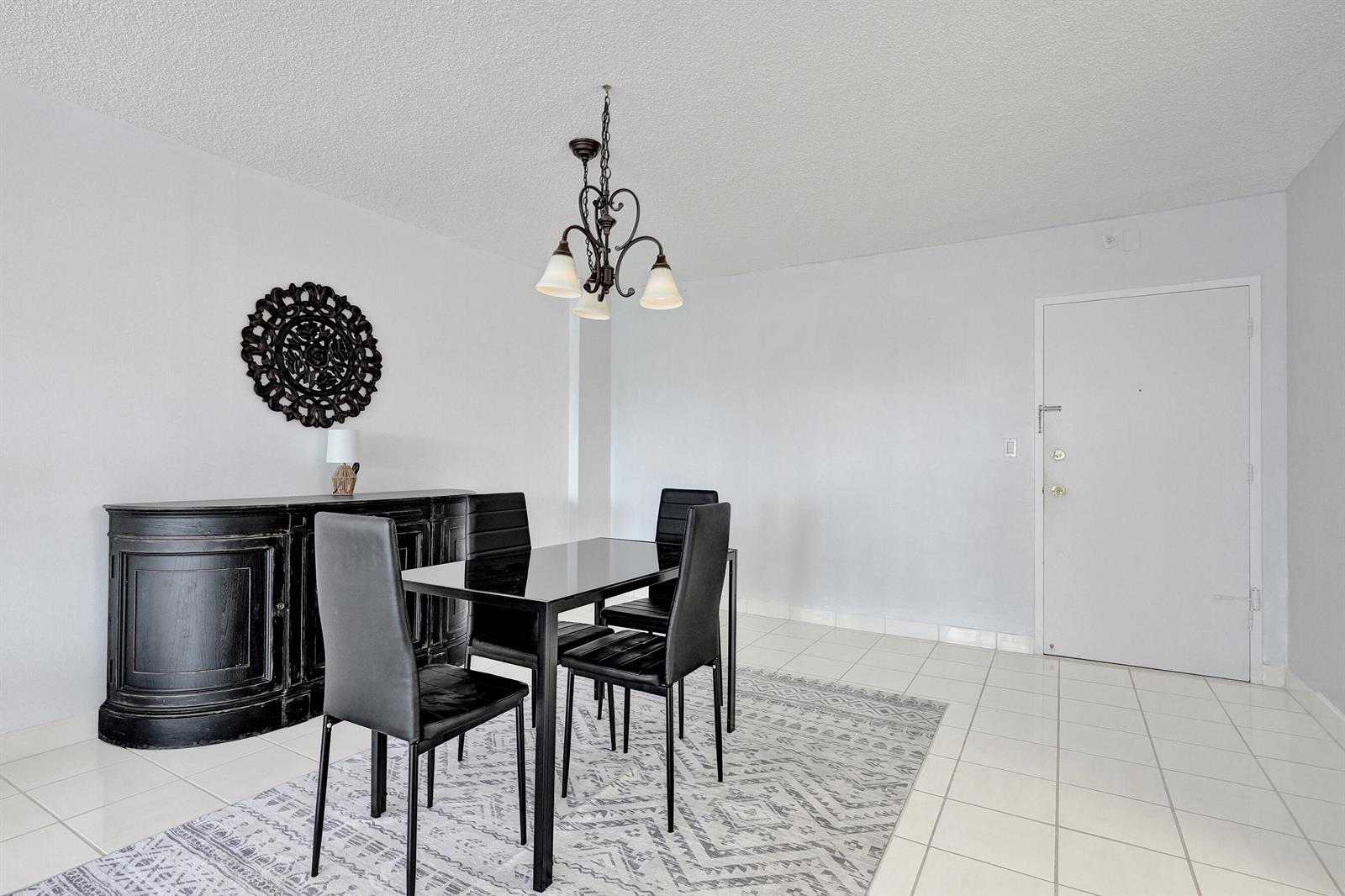 A dining room features a black table and chairs, a sideboard, and a patterned area rug — 405 N Ocean Boulevard # 305, Pompano Beach FL 33062, POMPANO BEACH, FL