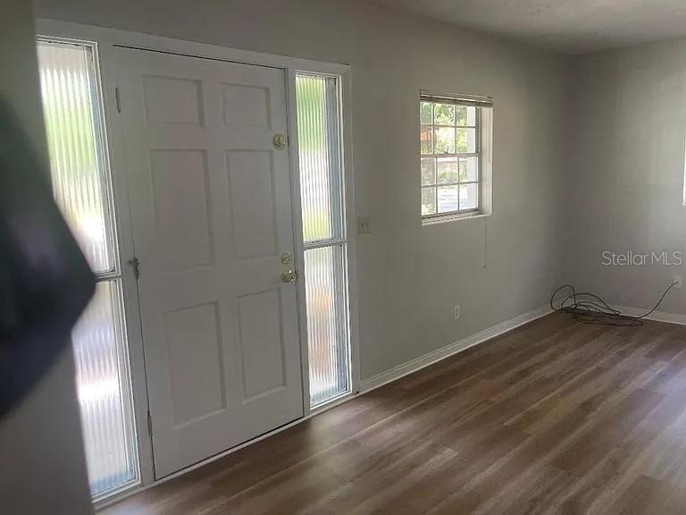 A room with light-colored walls, wood-look flooring, a white front door, and a window — 1701 NE 28TH AVENUE, GAINESVILLE, FL