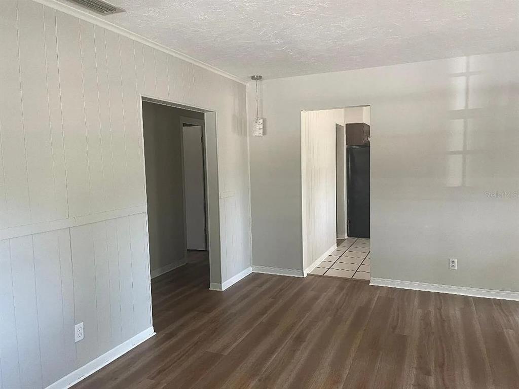 An interior view shows a living area with wood-look flooring and two doorways — 1701 NE 28TH AVENUE, GAINESVILLE, FL