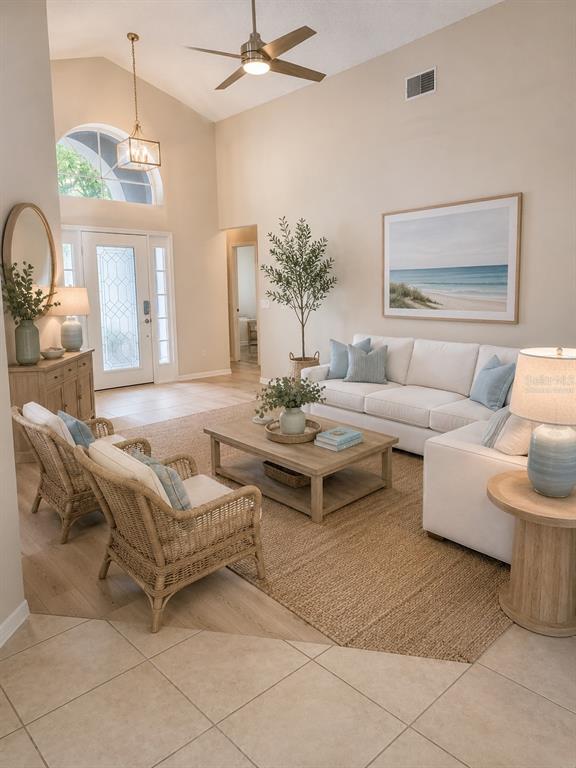 A bright living room features a white sofa, wicker armchairs, and a vaulted ceiling — 893 PADDINGTON TERRACE, LAKE MARY, FL