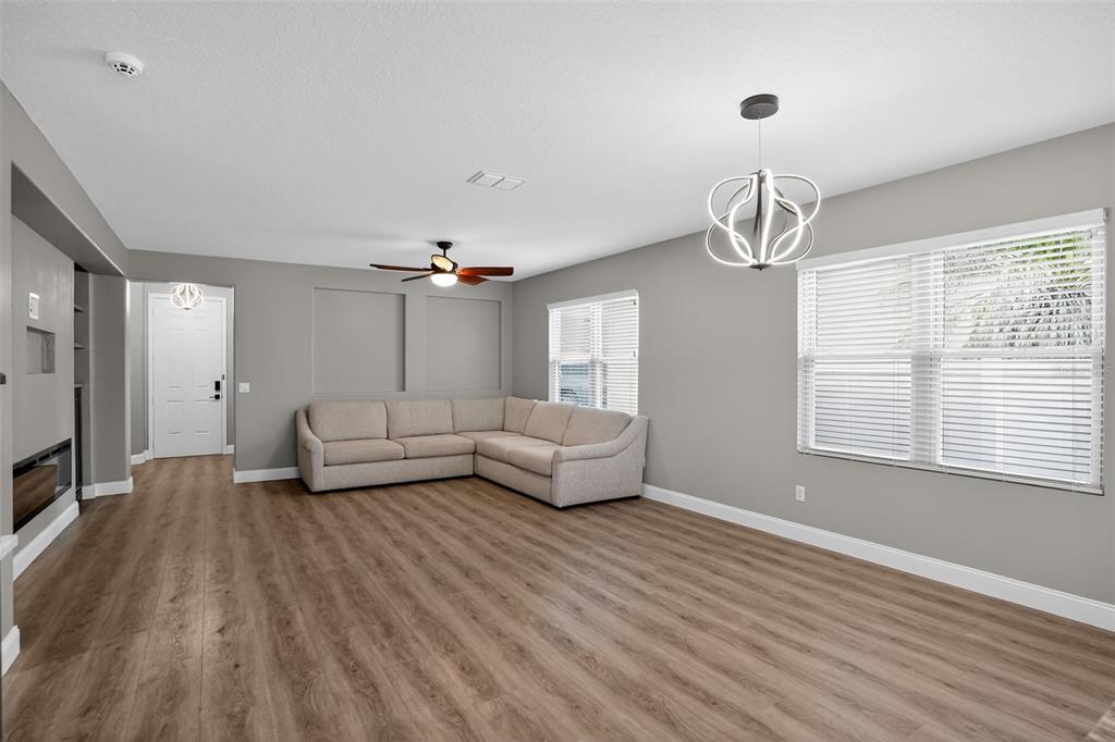 A living room features light gray walls, wood-look flooring, a sectional sofa, and a modern chandelier — 5036 HEARTLAND STREET, ORLANDO, FL