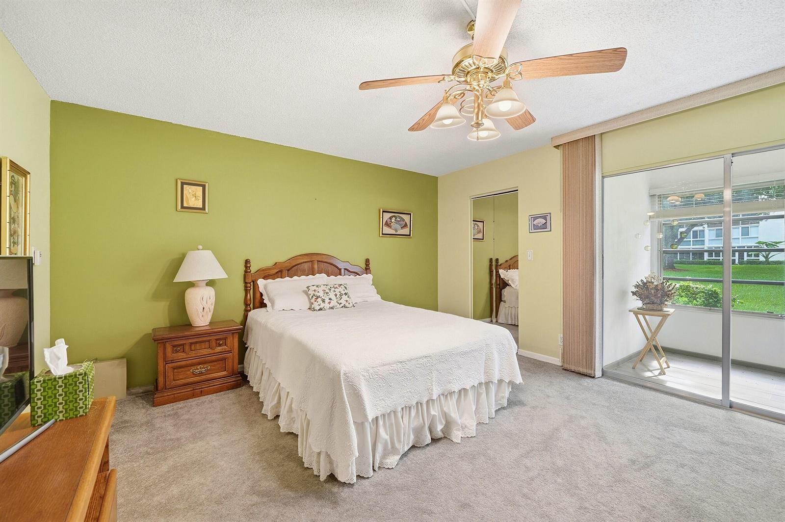 A bedroom with green walls, a queen bed, a ceiling fan, and a sliding glass door — 2302 Lucaya Lane # E1, Coconut Creek FL 33066, COCONUT CREEK, FL