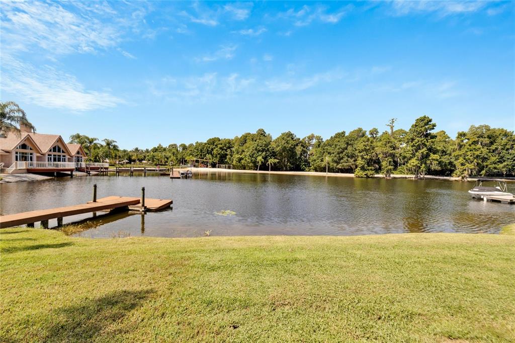 A grassy lawn overlooks a lake with a wooden dock and a house nearby — 17904 CACHET ISLE DRIVE, TAMPA, FL
