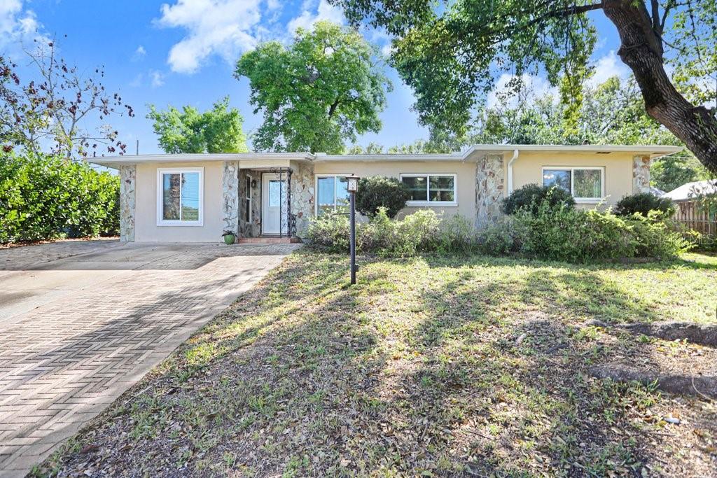 A single-story house with a stone facade, a brick driveway, and a front lawn — 6703 N RIVER BOULEVARD, TAMPA, FL