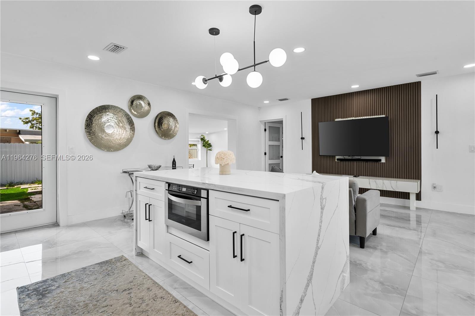 A modern kitchen island with a marble countertop sits in a bright, open-concept living space — 315 NW 106th ST, Miami FL 33150, MIAMI, FL