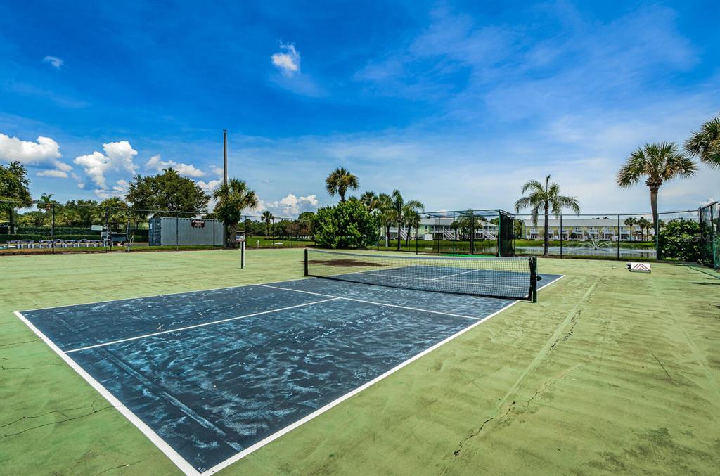 A pickleball court with a dark blue surface and a net under a blue sky — 5215 COQUINA KEY DRIVE SE UNIT B, ST PETERSBURG, FL