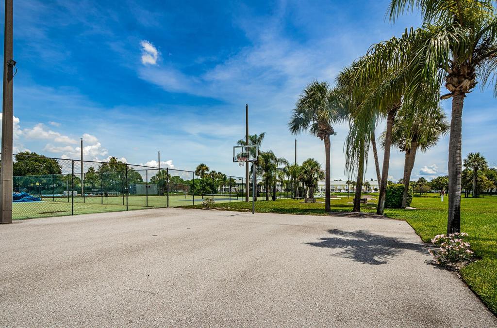 An outdoor basketball court sits next to a fenced tennis court surrounded by palm trees — 5215 COQUINA KEY DRIVE SE UNIT B, ST PETERSBURG, FL