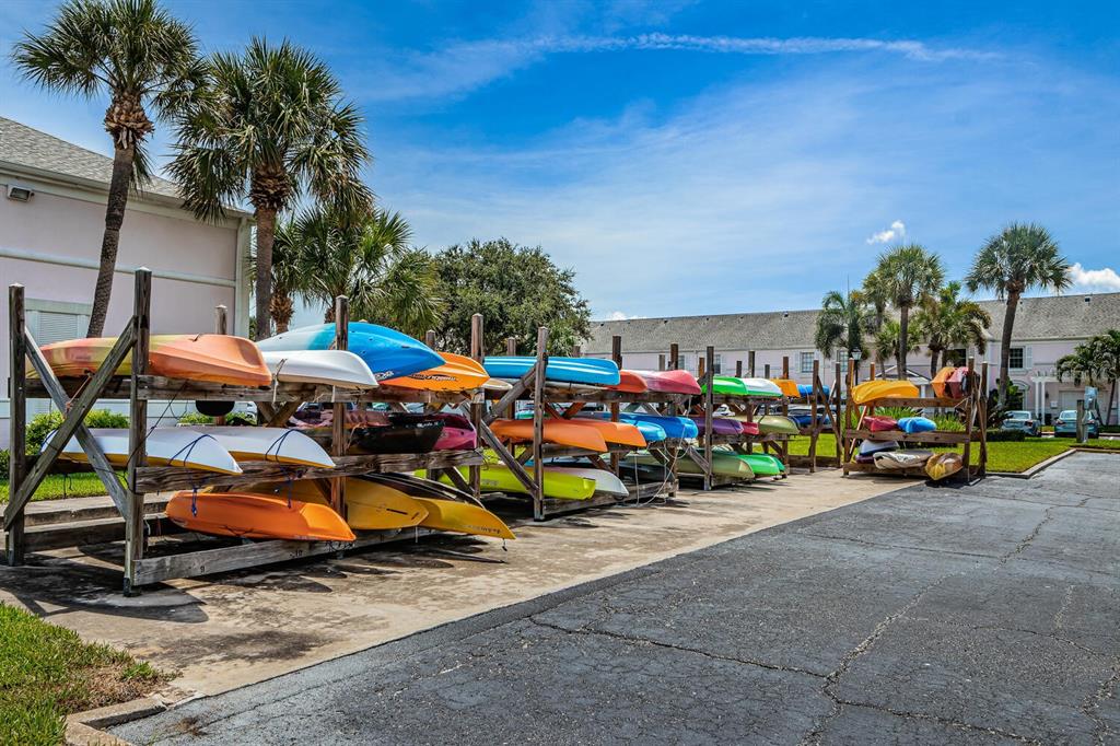 A wooden rack holds numerous colorful kayaks outdoors in a paved parking area — 5215 COQUINA KEY DRIVE SE UNIT B, ST PETERSBURG, FL