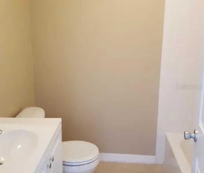 A bathroom features a white vanity, a toilet, and a bathtub with white wall tiles — 1235 MORGAN DRIVE, LAKELAND, FL