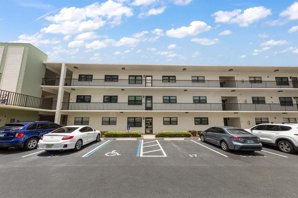A three-story apartment building exterior with a parking lot in the foreground — 5980 TERRACE PARK DRIVE N UNIT 310, ST PETERSBURG, FL