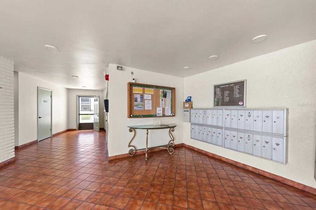 A building lobby features tiled floors, a bulletin board, a console table, and mailboxes — 5980 TERRACE PARK DRIVE N UNIT 310, ST PETERSBURG, FL