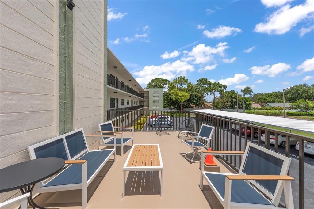 An outdoor balcony features patio furniture, a metal railing, and a view of the parking lot — 5980 TERRACE PARK DRIVE N UNIT 310, ST PETERSBURG, FL