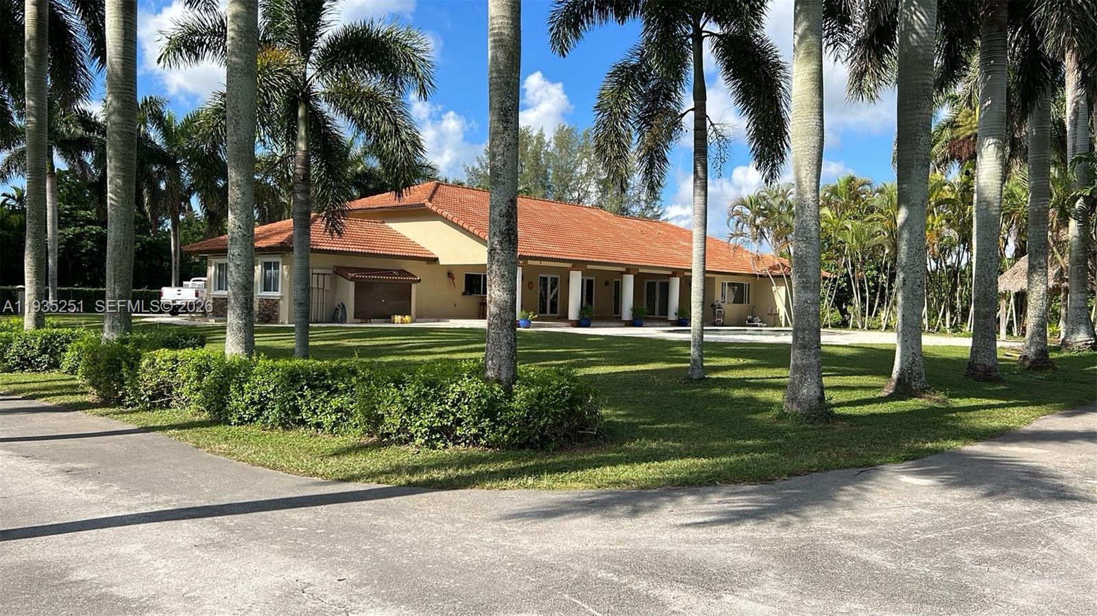 A single-story house with a terracotta tile roof sits on a grassy lot with palm trees — 19701 SW 197th Ave, Miami FL 33187, MIAMI, FL