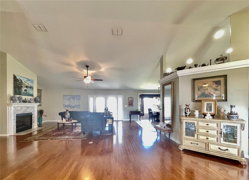 A spacious living room features hardwood floors, a fireplace, and an open dining area — 5525 SW 89TH PLACE, OCALA, FL