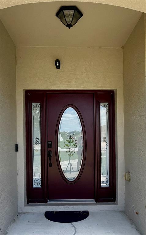 A front entryway features a dark red door with an oval glass insert and sidelights — 5525 SW 89TH PLACE, OCALA, FL
