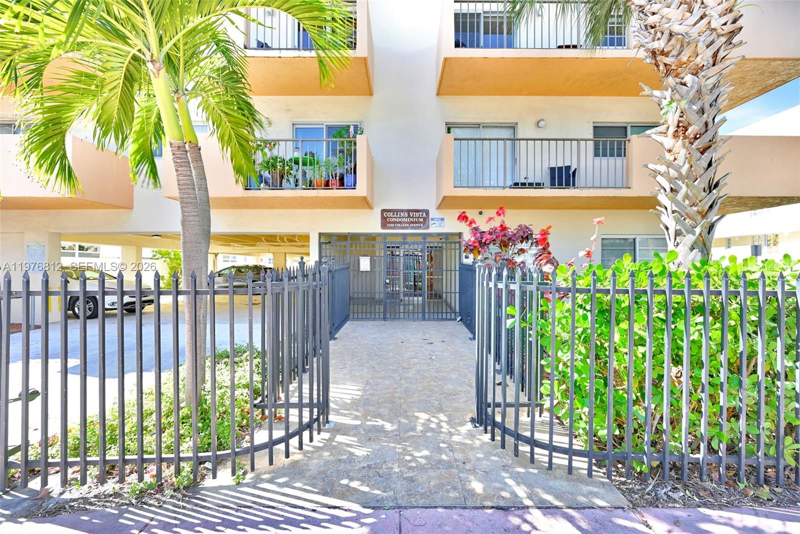 The exterior of a multi-story condominium building features a gated entrance and palm trees — 1150 Collins Ave # 405, Miami Beach FL 33139, MIAMI BEACH, FL