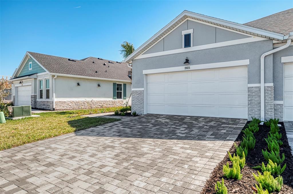 A paved driveway leads to the two-car garage of a modern suburban house — 2821 MARRAKESH LANE, SARASOTA, FL