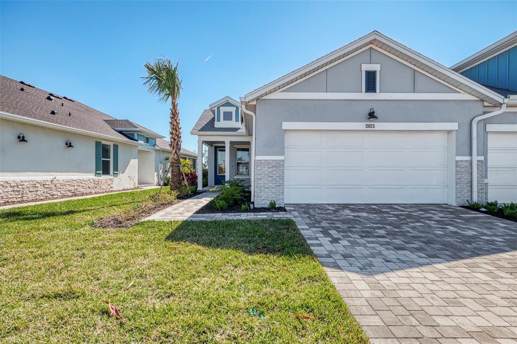 A single-story house with a gray stucco exterior, stone accents, and a paved driveway — 2821 MARRAKESH LANE, SARASOTA, FL