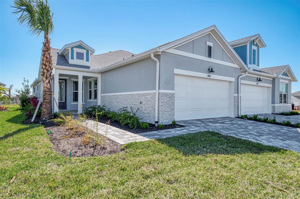 A gray stucco and stone exterior of a two-car garage home with a palm tree — 2821 MARRAKESH LANE, SARASOTA, FL