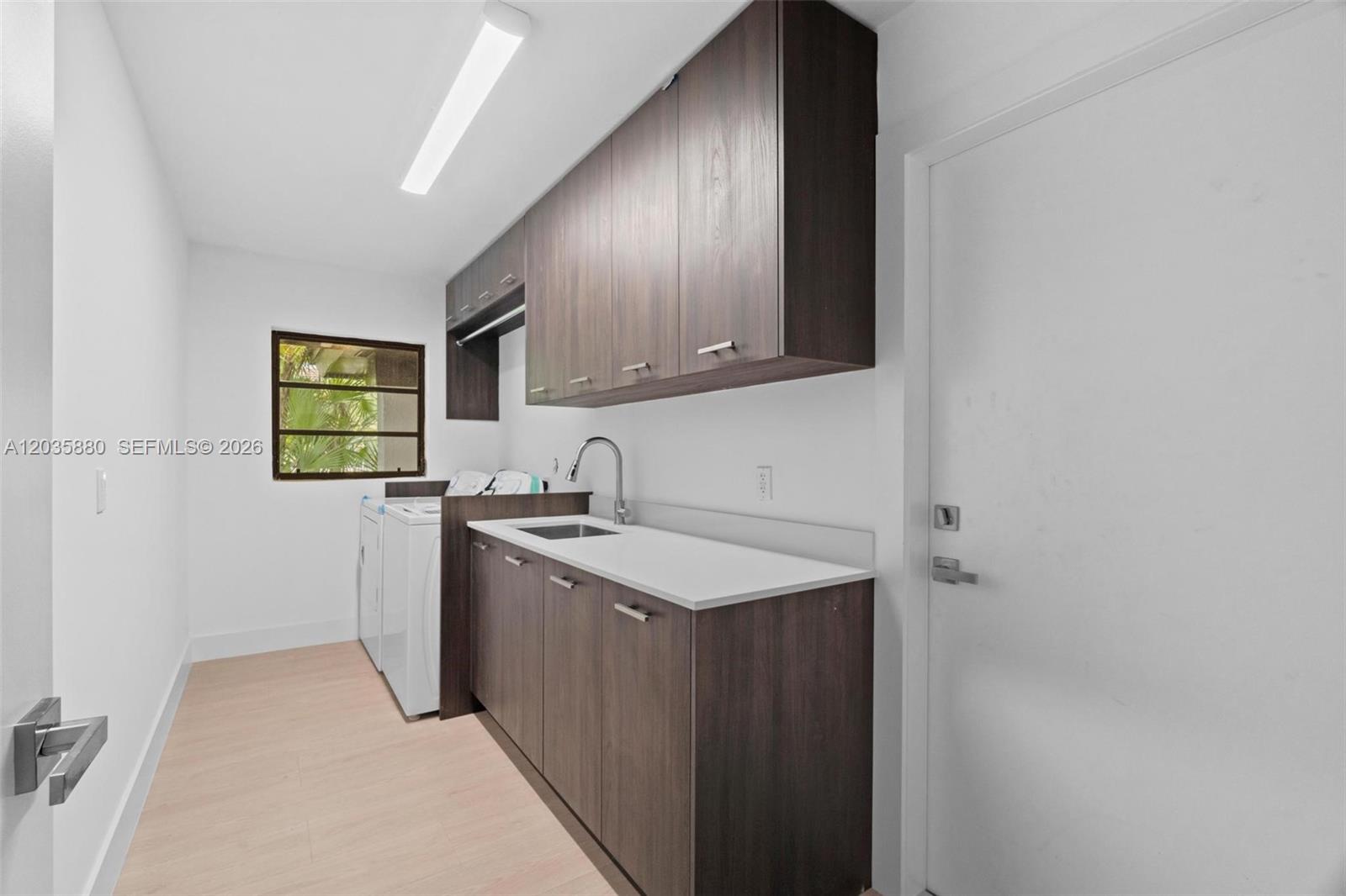A laundry room features dark wood cabinets, a white countertop with a sink, and appliances — 5254 NW 94th Doral Pl, Doral FL 33178, DORAL, FL