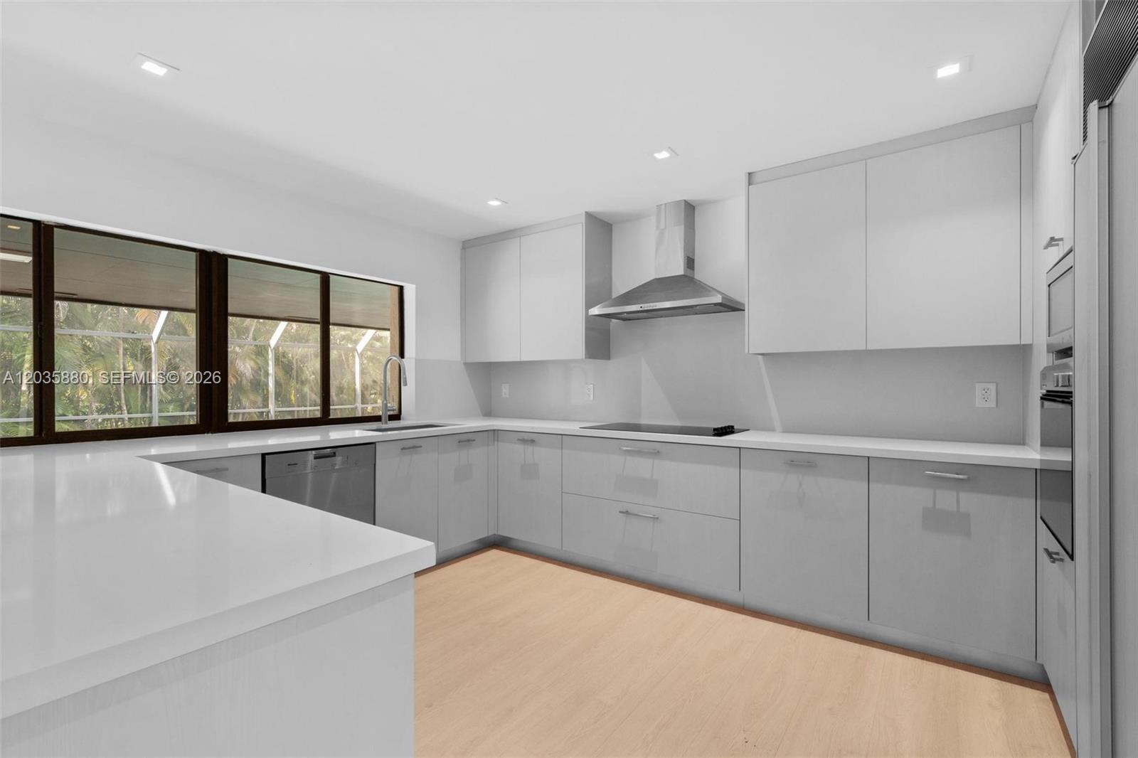 A modern kitchen features light gray cabinets, white countertops, stainless steel appliances, and large windows — 5254 NW 94th Doral Pl, Doral FL 33178, DORAL, FL