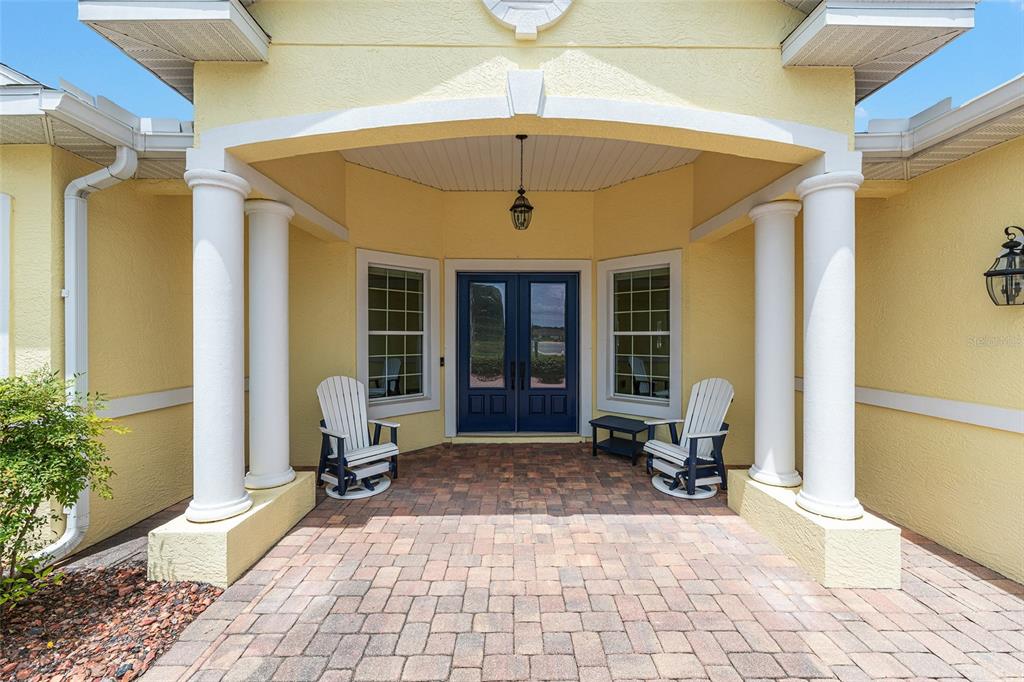A paved entryway features two white chairs, a blue double door, and two white columns — 8671 SW 83RD LOOP, OCALA, FL
