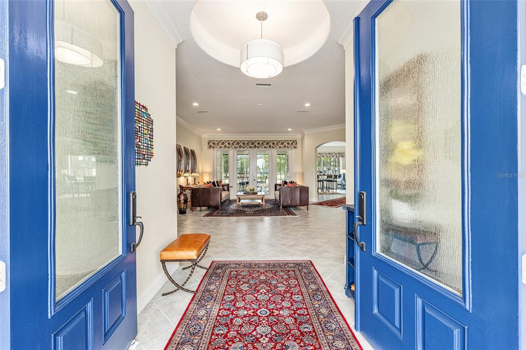 A view through blue double doors into a foyer with a red patterned rug — 8671 SW 83RD LOOP, OCALA, FL