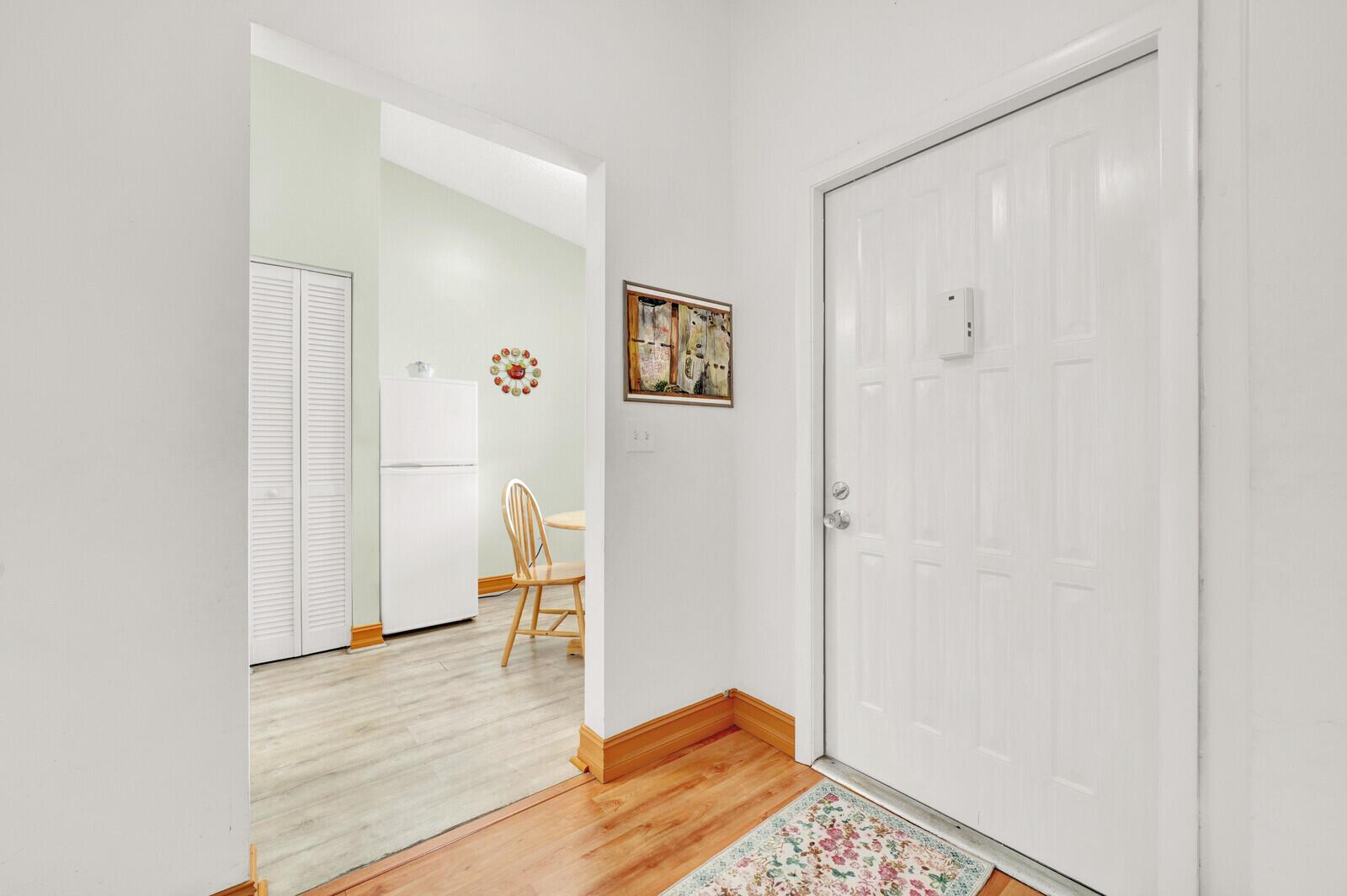 An entryway with a white door leads into a kitchen featuring light wood-look flooring — 7867 Willow Spring Drive # 821, Lake Worth FL 33467, LAKE WORTH, FL