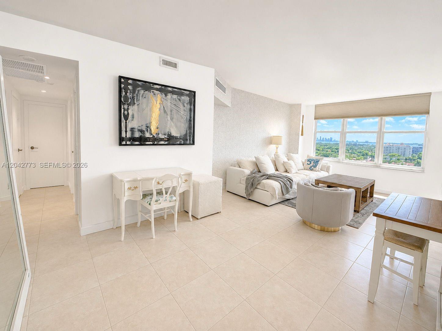 A bright living room features tile floors, a white sofa, and a view of the city — 4747 Collins Ave # 1101, Miami Beach FL 33140, MIAMI BEACH, FL