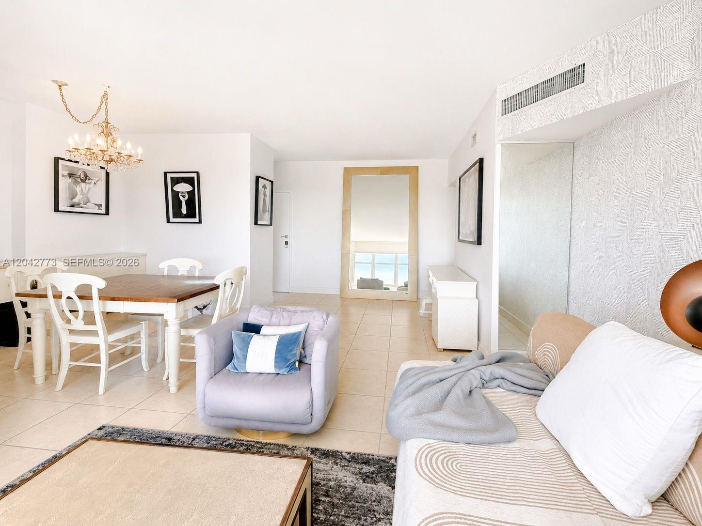 This living and dining area features white walls, tile flooring, and a large floor mirror — 4747 Collins Ave # 1101, Miami Beach FL 33140, MIAMI BEACH, FL