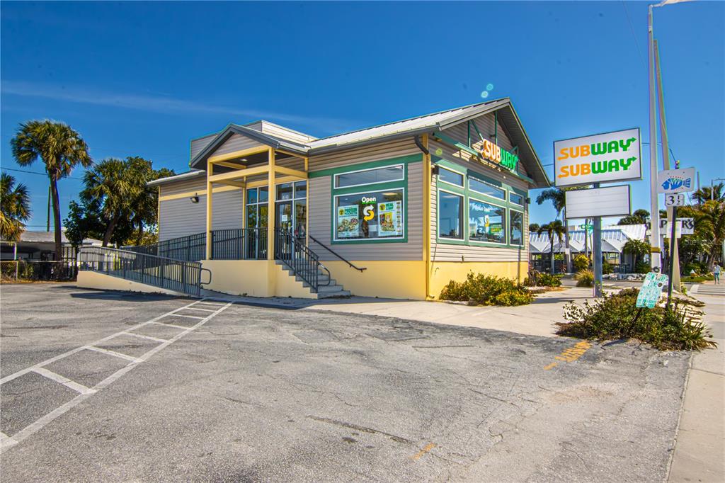 A Subway restaurant building with a parking lot, ramp, and signage under a clear sky — 5901 GULF BOULEVARD, ST PETE BEACH, FL