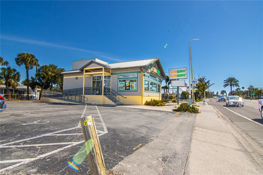 A Subway restaurant building with a parking lot and ramp entrance under a clear sky — 5901 GULF BOULEVARD, ST PETE BEACH, FL