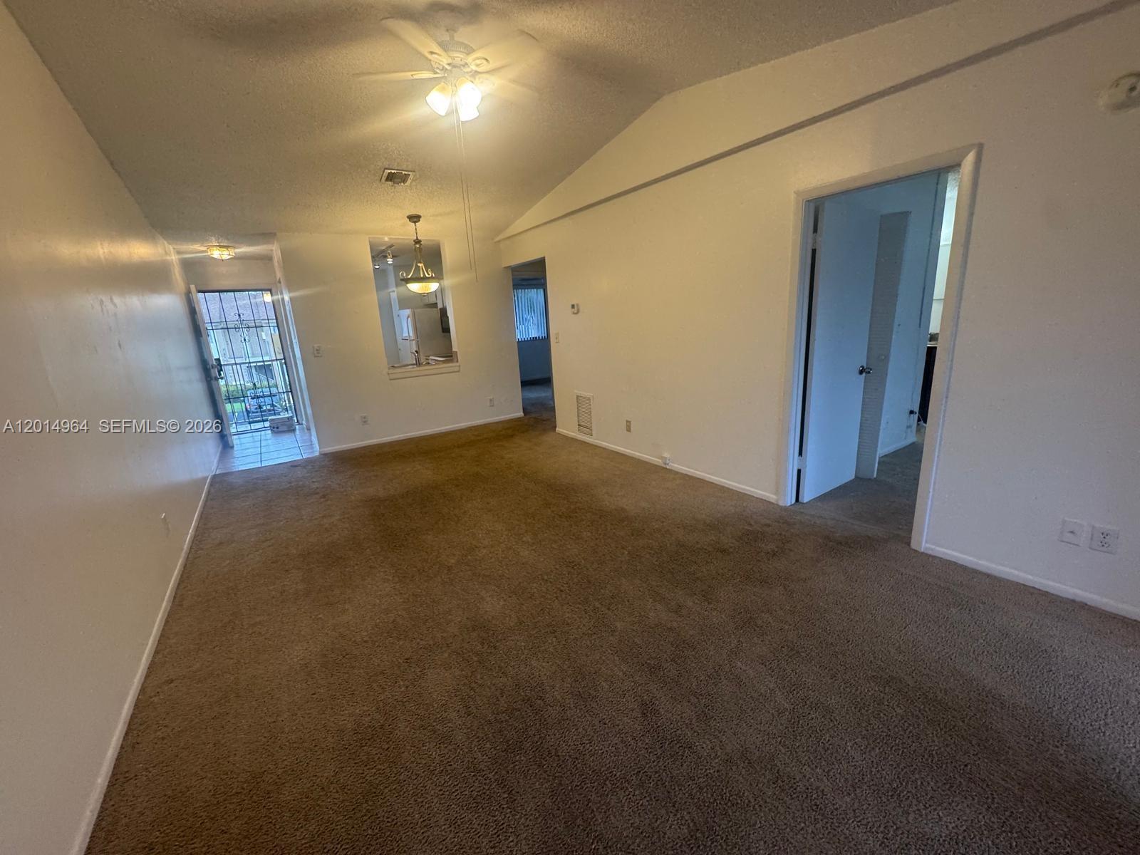 An empty living room features brown carpet, white walls, a ceiling fan, and an entryway — 142 NW 60th Ave # 2, Margate FL 33063, MARGATE, FL