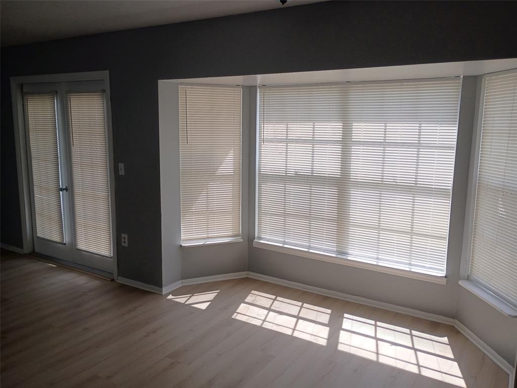 A room with light wood flooring, gray walls, a bay window with blinds, and glass doors — 1359 PRIMROSE COURT, LAKELAND, FL