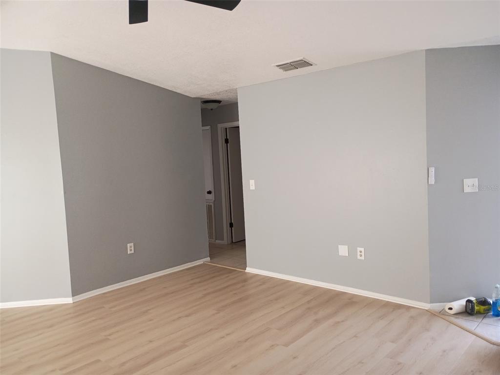An empty room features light gray walls, light wood-look flooring, and a doorway leading elsewhere — 1359 PRIMROSE COURT, LAKELAND, FL